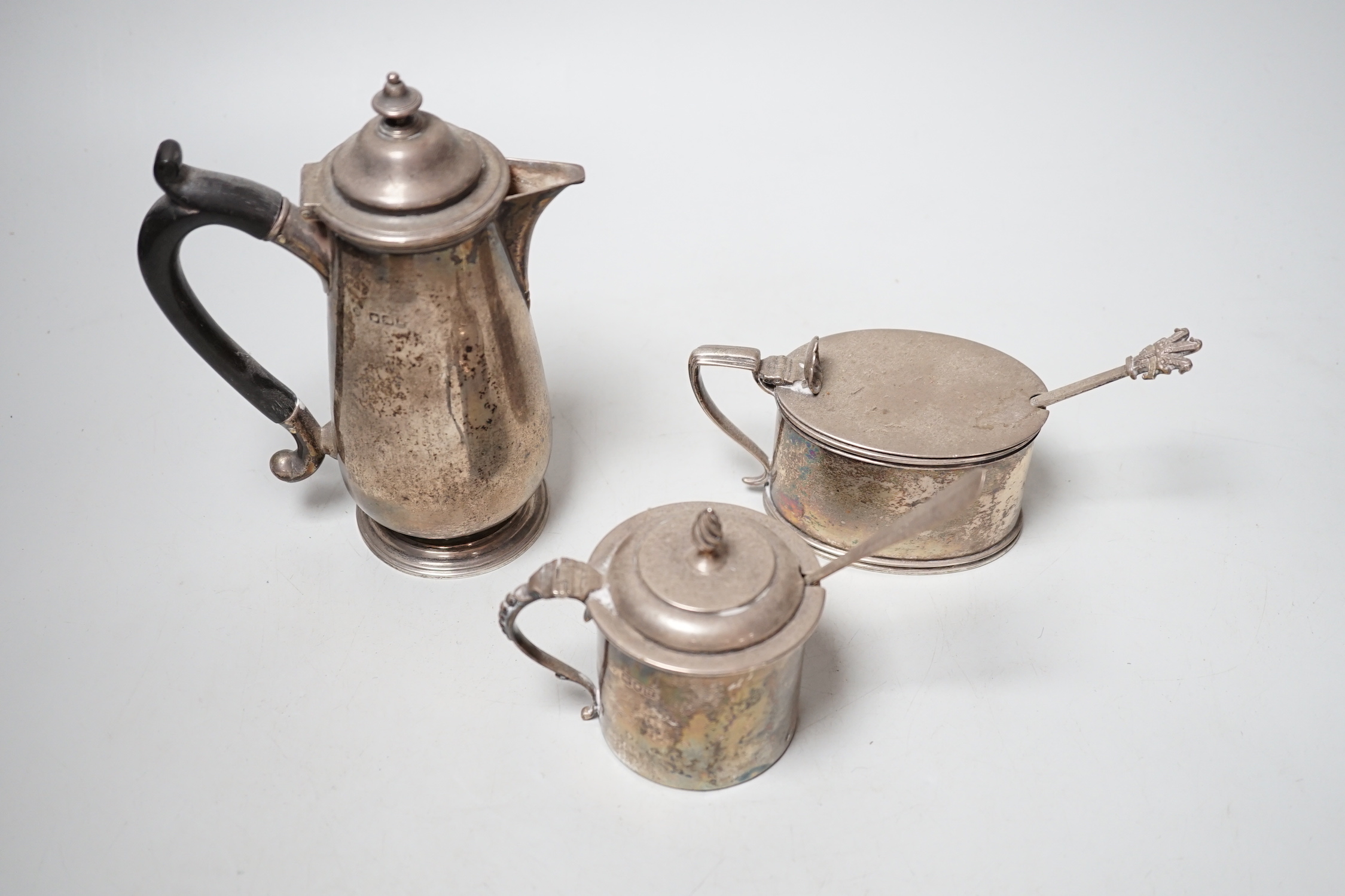 An early 20th century silver hot water pot and two silver mustard pots.